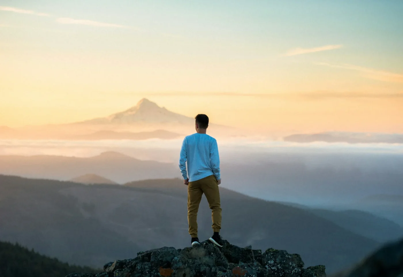 a man standing on the mountain top looking at the world